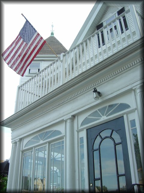 American flag above the entrance of a large white house