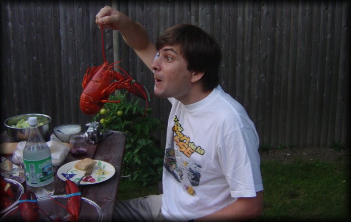 Philippe holding a lobster by the antenna and making faces at it