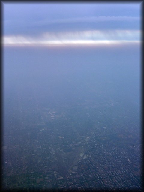 View from the plane on a distant city, haze and dripping clouds