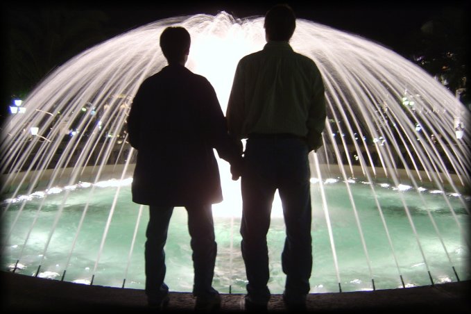 Robin and Mason standing in front of a brightly lit fountain, Monaco