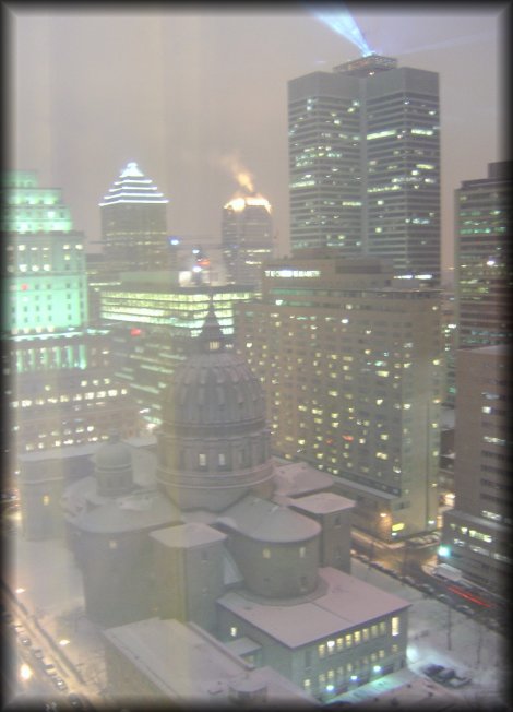 Montreal by night, snow on the roofs and there is a building in the backgroudn which top looks on fire
