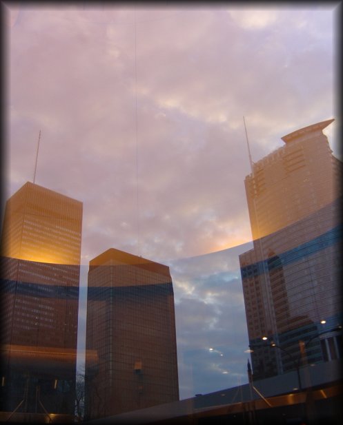 Three buildings reflected in the glass door of 1000 la gauchetiere.