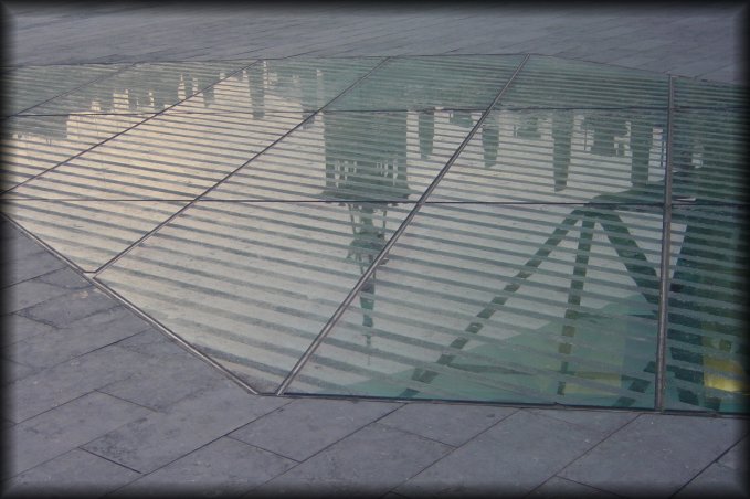 La Caixa cultural centre reflected on a glass surface of the sidewalk