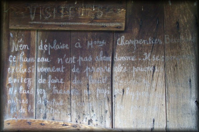 A note to visitors written with chalk, informing this is not an abandoned village.