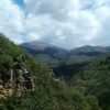 Some rocks, mountains, more mountains, a little snow at the top, clouds and a very blue sky
