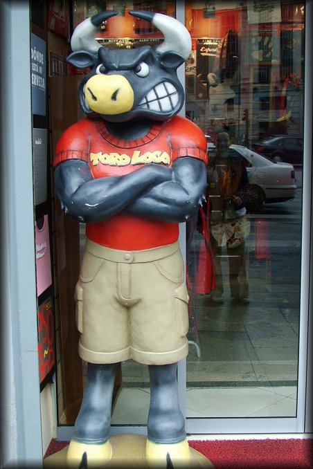 A Toro Loco statue guarding the entrance of a shop. Reflection of Isabelle in the window next to it.