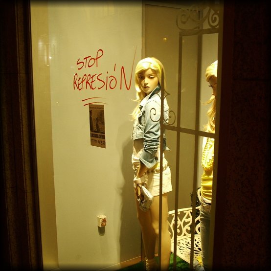 "Stop Repression" hand written on a shop window above a press clipping 