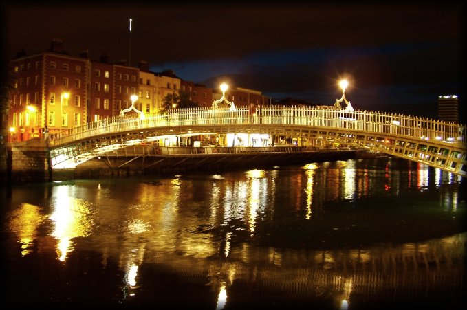 Illuminated bridge over River Liffey. The light at the top on the left is the tip of the Spike of Dublin.