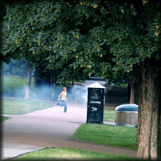 Boy running in the Vigeland Sculpture Park, just behind smoke that comes from the special contain for engangsgrills.