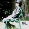 Reuben, the young man in grey and black, sitting on a green bench, under his black bowler hat.