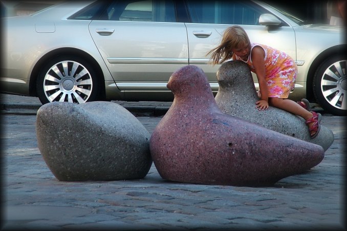 A little girl climbing a stone bird