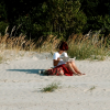 All by herself... on the sand, in the sun, with her paper