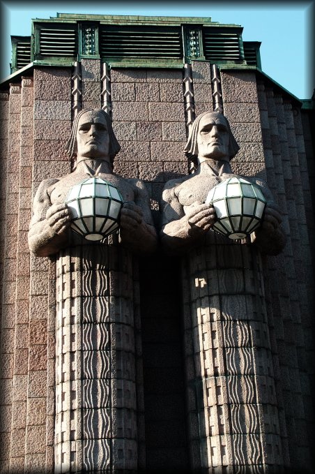 Next to the entrance of the Helsinki train station. Because of the angle, the statue on the right seems to be leaning on the one of the left. 