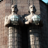 Next to the entrance of the Helsinki train station. Because of the angle, the statue on the right seems to be leaning on the one of the left. 